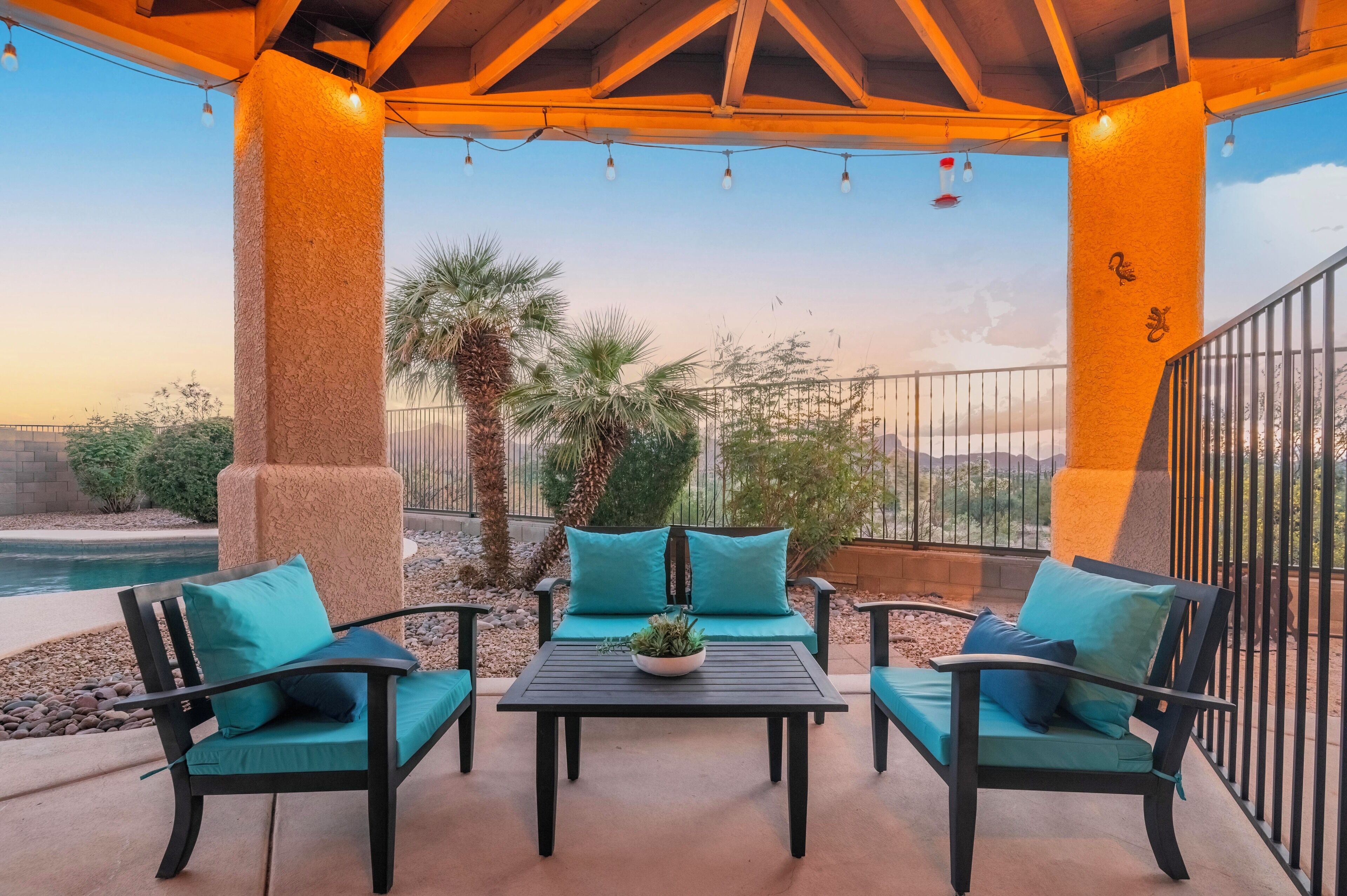 Un patio exterior con mesa y sillas, piscina y vistas del paisaje circundante.