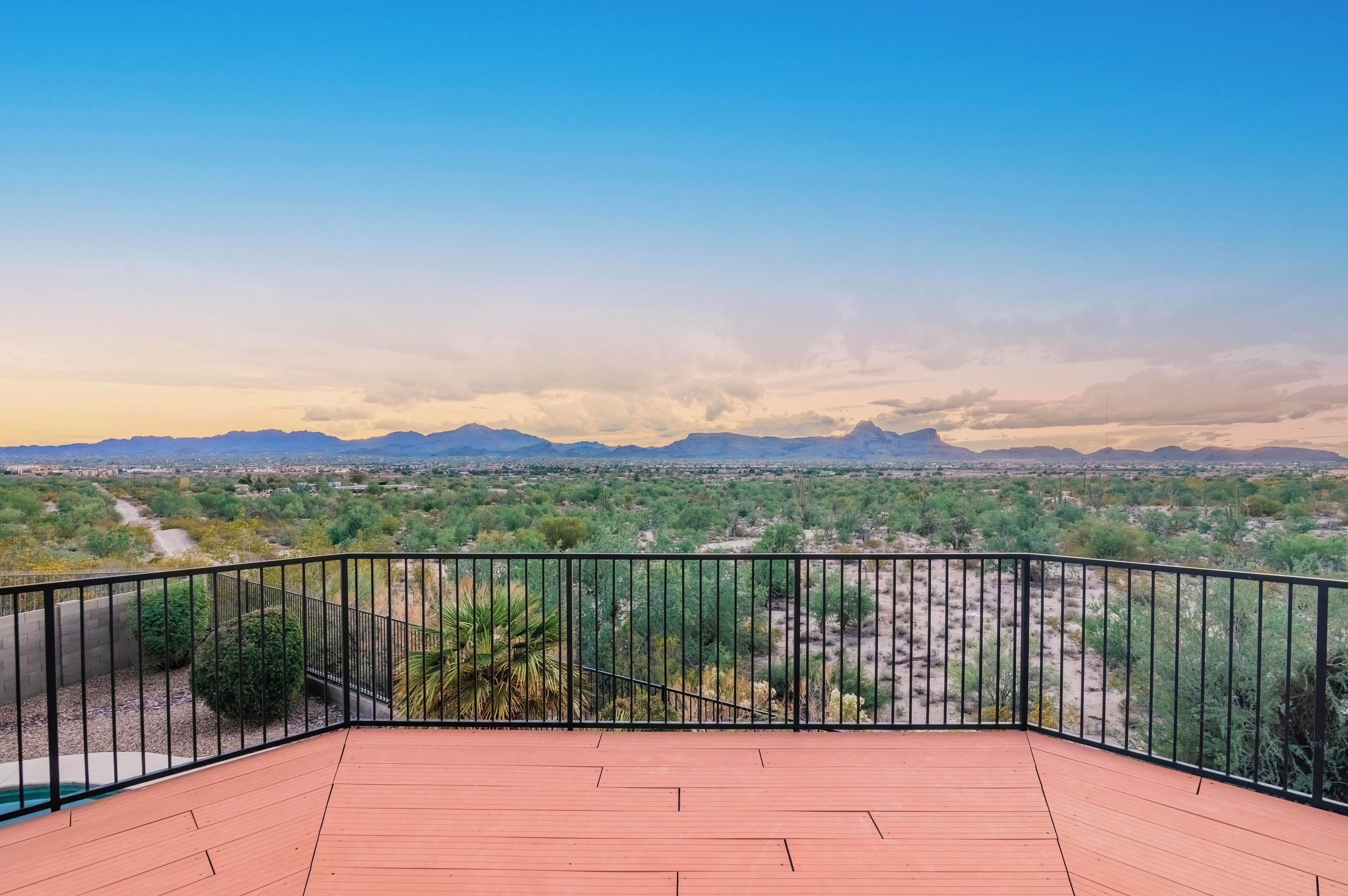 A balcony with a view of a desert landscape and distant mountains.