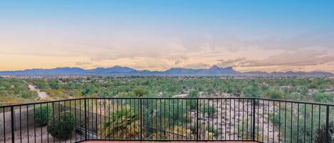 A balcony with a view of a desert landscape and distant mountains.