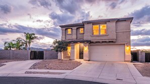 A two-story house with a garage, a driveway, and a landscaped front yard with a palm tree. - Serene desert escape w/ stunning mountain views & heated pool/spa- pet friendly! (Tucson)