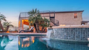 A swimming pool with a waterfall feature, lounge chairs, and a modern building with a spiral staircase. - Serene desert escape w/ stunning mountain views & heated pool/spa- pet friendly! (Tucson)