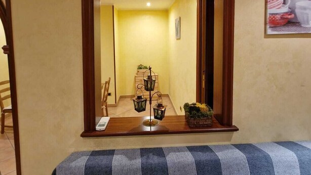A room with a large arched doorway, a wooden bench, a small table with a plant, and a painting on the wall. - Two steps from the heart of Rome. (Roma)