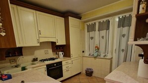 A kitchen with white cabinets, a stove, and a sink. - Two steps from the heart of Rome. (Roma)