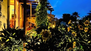 Ein Haus mit überdachter Veranda, einem Garten mit Sonnenblumen und Blick zum Himmel.
