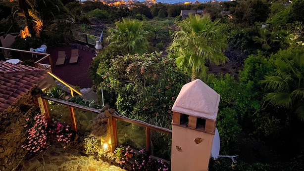 A coastal view with a stone tower, lush greenery, and a patio area with outdoor seating.