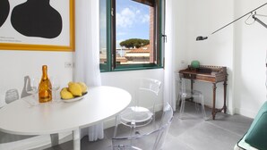 A modern room with a white table, clear chairs, a bottle, and glasses. - Design Flat (Piano di Sorrento)