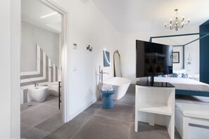 A modern bathroom with a freestanding bathtub, a vanity with a mirror, and a shower area. - Design Flat (Piano di Sorrento)