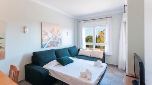 A modern room with a sofa bed, a flat-screen TV, and a painting on the wall. - Camelot in Oliva With 1 Bedrooms and 1 Bathrooms (Oliva)