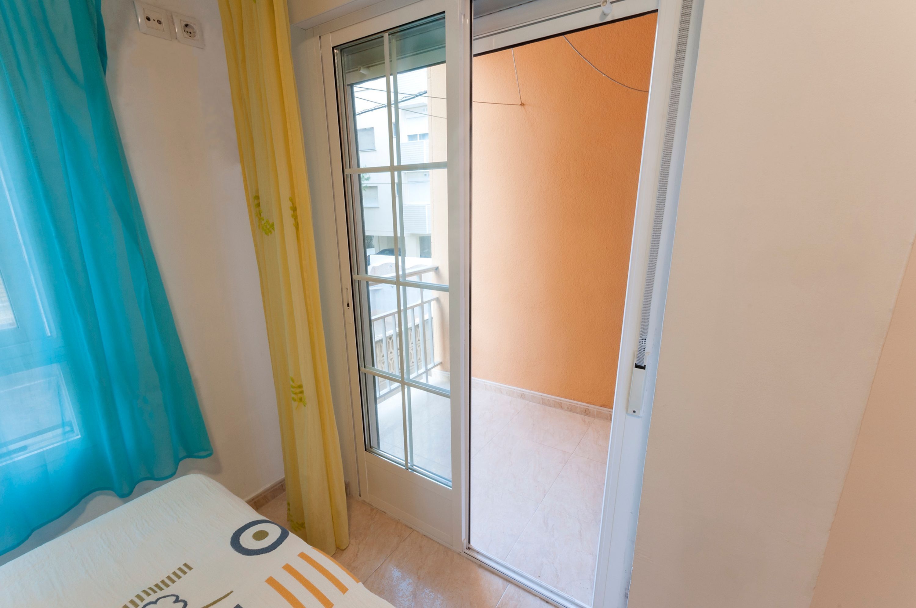 A room with a sliding glass door leading to a balcony.