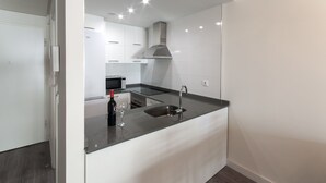 Een moderne keuken met witte kasten, een roestvrijstalen afzuigkap, een inbouwmagnetron en een zwart aanrecht.