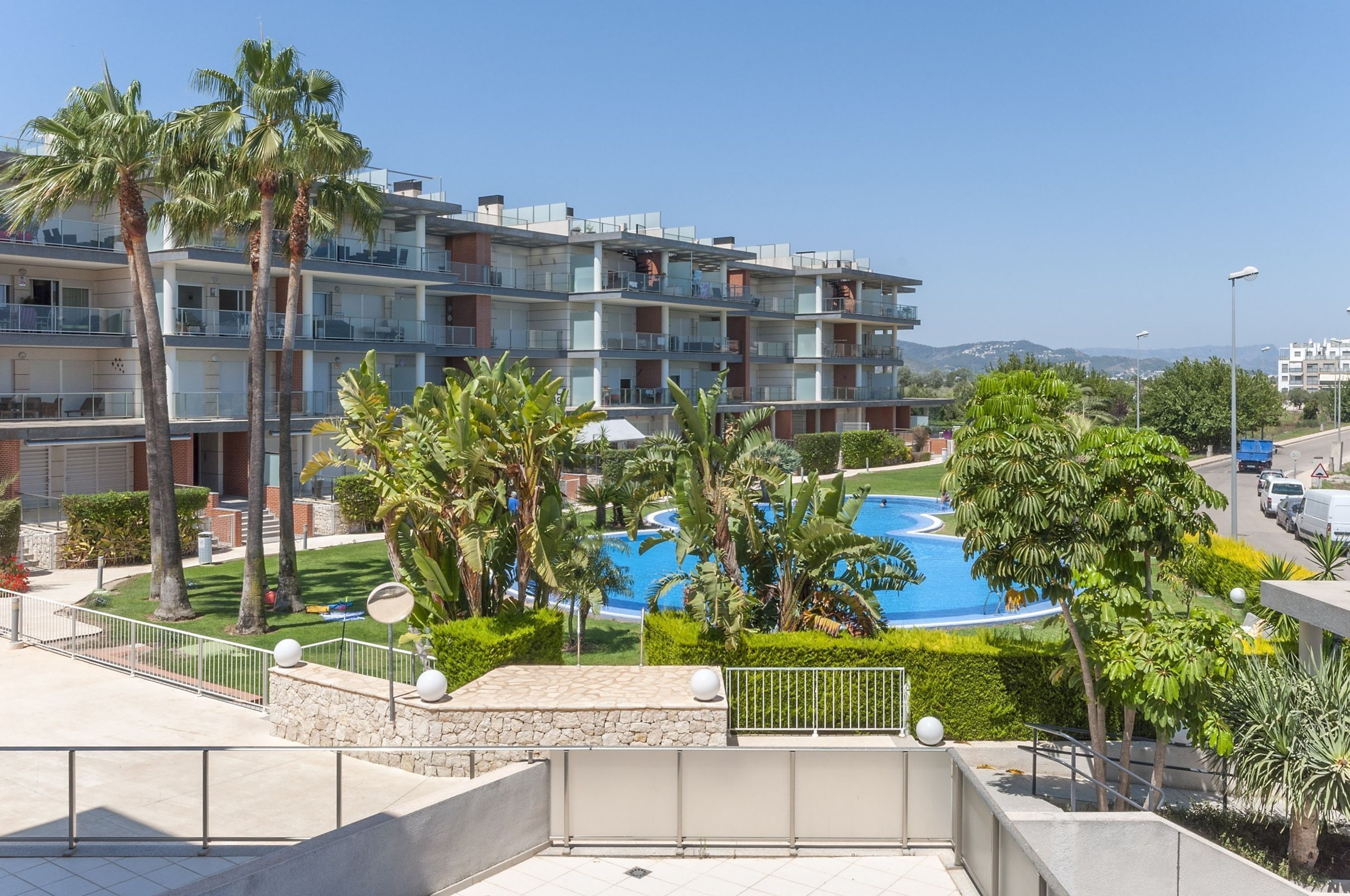 Un hôtel à plusieurs étages doté de balcons, d’une piscine et de palmiers.