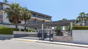 Een modern gebouw met een overdekte ingang, palmbomen en een stenen muur.
