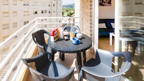 A balcony with a table and chairs, a bottle, a box of biscuits, and a cup. - Bambu in Grau i Platja (Gandia)