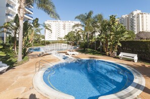 A swimming pool surrounded by palm trees and a white fence. - Alejandrita in Grau i Platja (Gandia)
