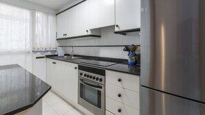Een moderne keuken met witte kastjes, een roestvrijstalen koelkast, een inbouwoven en een zwart aanrecht.