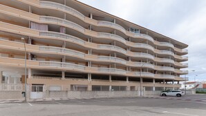 Een meerlaags woongebouw met balkons, een parkeergarage en een straatbeeld.