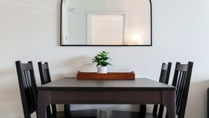 A dining table with a mirror above it, surrounded by chairs, and a small potted plant on the table.