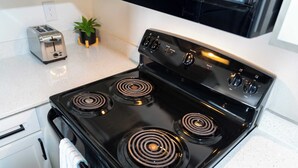 A kitchen with a black stove, a toaster, and a small potted plant on the counter. - Modern Poolside Apartment Near Gruene (New Braunfels)