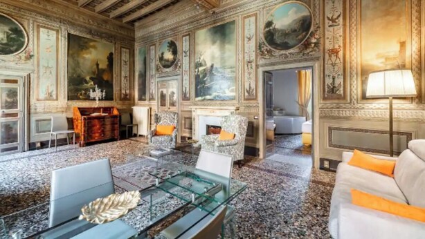 A luxurious room with ornate ceiling, large paintings, and classic furniture.