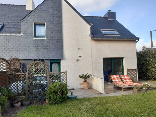 Una casa a due piani con un balcone e un piccolo giardino.