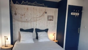 A bedroom with a bed, two bedside tables, a wall-mounted lamp, and a door. - Maison Presqu'ile de Gâvres (Gâvres)