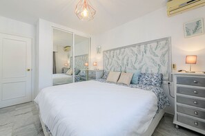 A bedroom with a large bed, a dresser, a mirror, and a ceiling light fixture. - Benalmar Playa in Benalmadena (Benalmádena)