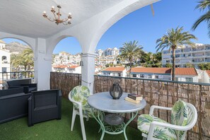 A balcony with white wicker furniture, a round table, and a decorative vase. - Benalmar Playa in Benalmadena (Benalmádena)