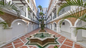 A courtyard with a central fountain, white walls, and red-tiled flooring. - Benalmar Playa in Benalmadena (Benalmádena)