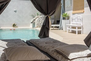 A poolside area with a bed, a chair, and a view of the pool. - Calymar in Navahermosa (Sierra de Yeguas)