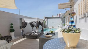 Un patio moderno al aire libre con piscina, zona de estar y plantas en macetas.