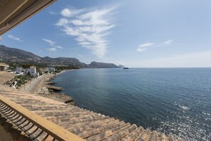 A coastal view with steps leading down to the water, a clear sky, and distant mountains.