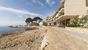 Un hôtel en bord de mer, avec un sentier en pierre menant à la plage, doté de balcons et offrant une vue sur la mer.