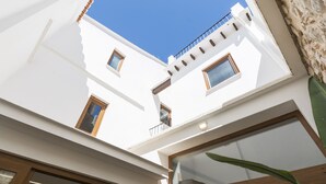 Un bâtiment moderne aux murs blancs, doté de nombreuses fenêtres et d’un balcon.