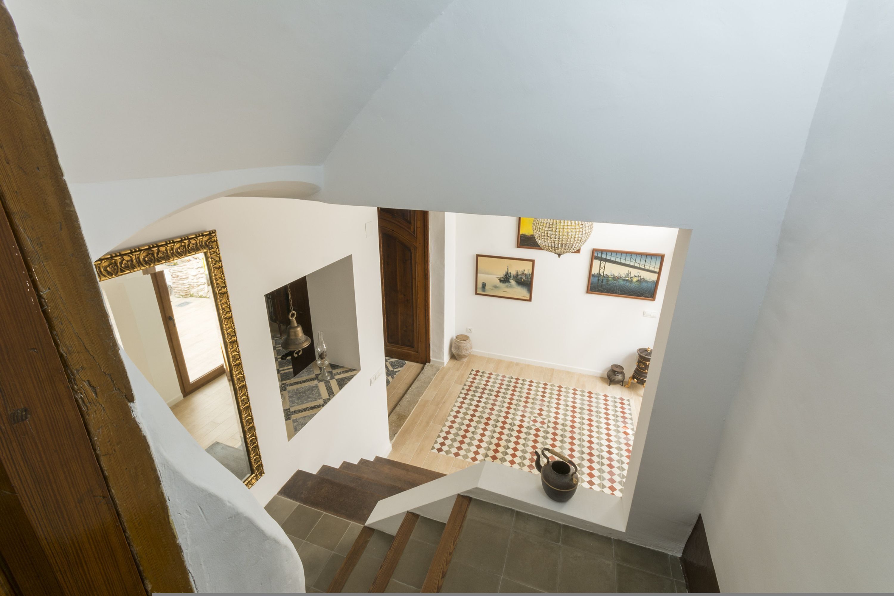 A staircase leading to a room with a patterned floor, a wooden door, and a framed picture on the wall.