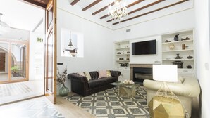 Un salon moderne comprenant un canapé, une table basse, un téléviseur et des étagères ornées d’objets décoratifs.