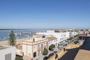 A coastal town with buildings along the waterfront, a clear sky, and boats docked at the pier.