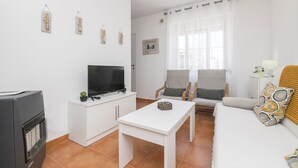 A modern living room with a flat-screen TV, white furniture, and decorative wall art. - Apartamento Enjoy Tarifa (Tarifa)