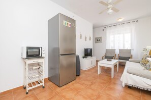 A compact living space with a refrigerator, microwave, TV, and seating area. - Apartamento Enjoy Tarifa (Tarifa)