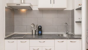 A modern kitchen with white cabinets, a stainless steel sink, and a built-in range hood. - Apartamento Enjoy Tarifa (Tarifa)