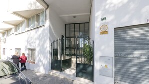 Entrada d'un edifici amb una reixa de metall, una porta de garatge i un senyal amb el número de l'adreça.