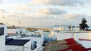 A rooftop view of a residential area with buildings, a beach in the background, and a clear sky. - Altamar in Conil de la Frontera (Conil de la Frontera)