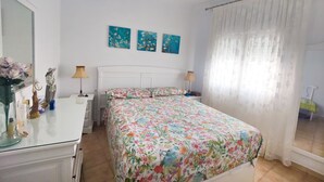 A bedroom with a bed, two bedside tables, a dresser, a mirror, and floral artwork on the wall. - Altamar in Conil de la Frontera (Conil de la Frontera)