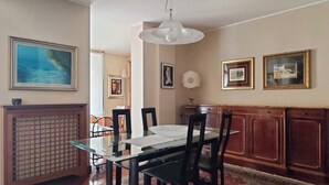 Comedor con mesa de vidrio, sillas negras, alfombra estampada y armarios de madera.