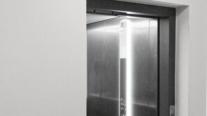 An elevator with a metallic finish and a control panel with buttons.