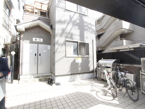 A residential building with a tiled exterior, a bicycle parked outside, and a visible staircase leading to an upper floor.