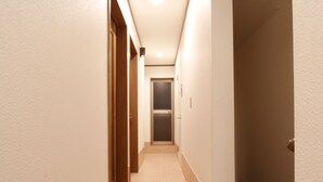 A narrow, well-lit hallway with a tiled floor and wooden doors on one side. - 202_Shinjuku Gourmet&Shopping Recently (新宿区)