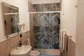 A bathroom with a sink, mirror, and shower.