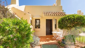 A Mediterranean-style building with a tiled roof, a small porch, and a door.