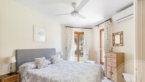 A bedroom with a bed, bedside tables, a wardrobe, and a ceiling fan.