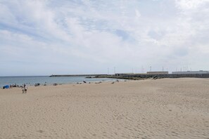 A wide sandy beach with a pier in the distance, a few people, and a clear sky. - Balcon Del Atardecer (Barbate)